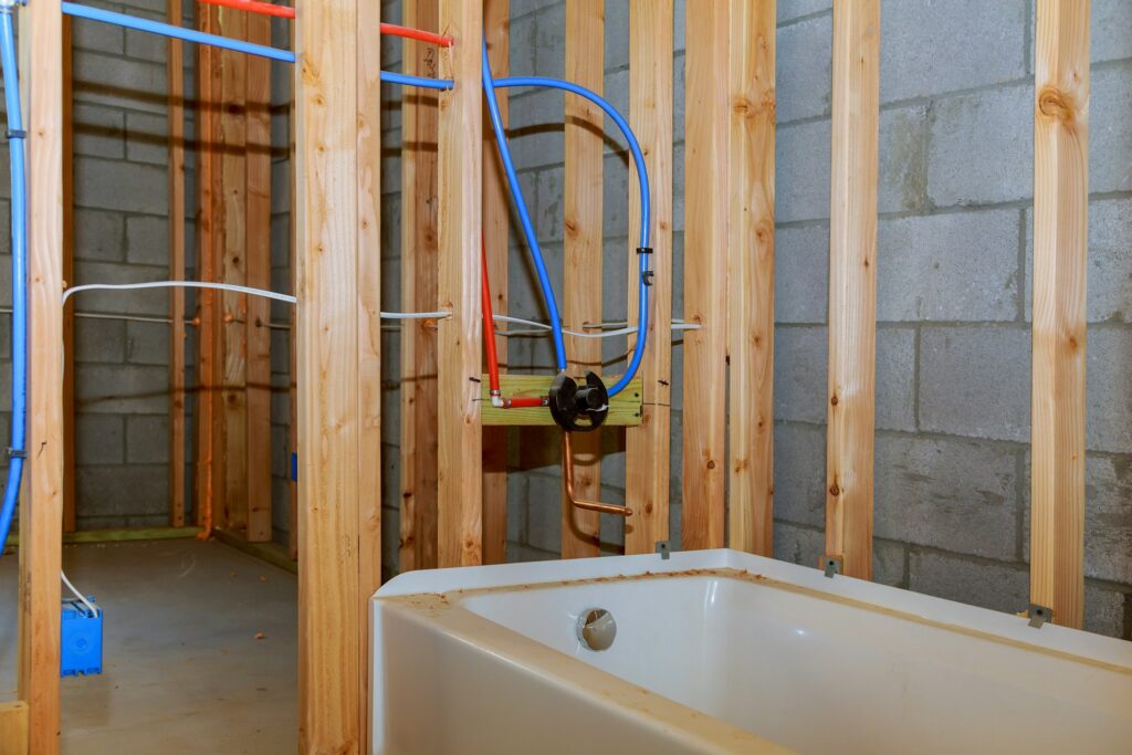 Bathroom remodel showing under floor plumbing work connecting old copper pipes to new plastic ones